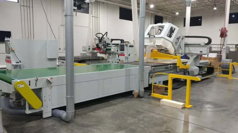 Stratos Pro CNC router line with a green infeed conveyor and dust collection ducting