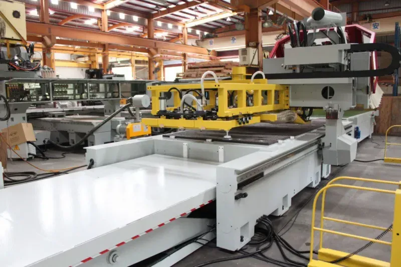 Stratos Pro CNC router with a yellow automatic loading gantry over its white worktable